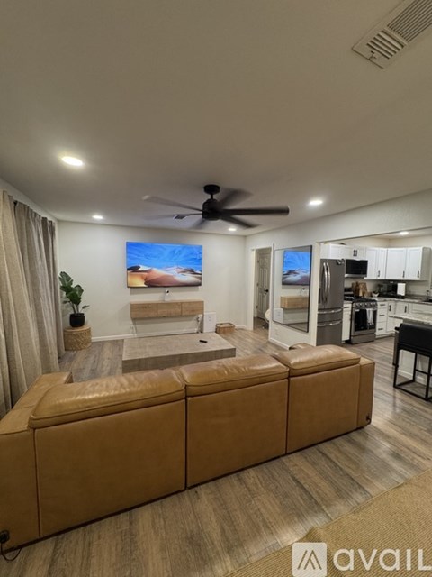 A living room with a brown leather sofa and a ceiling fan.