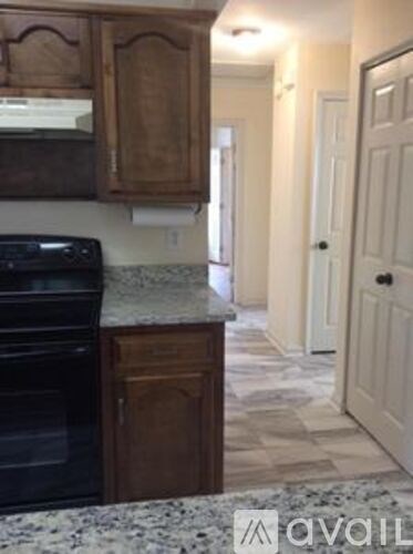 A kitchen with a granite counter top and wooden cabinets.