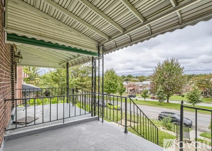 A balcony with a metal railing and a view of a street.