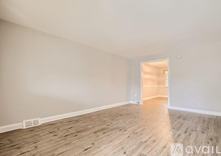 A room with wooden flooring and a doorway leading to another room.