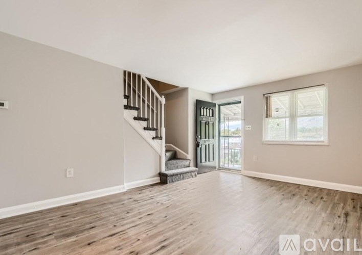 A spacious room with wooden floors and a staircase leading to another room.