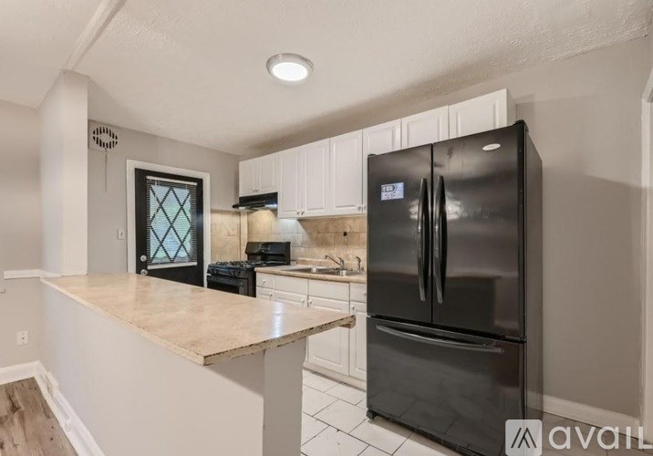 A black refrigerator in a kitchen with white cabinets.