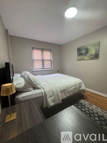 A bedroom with a bed, lamp, and a painting on the wall.
