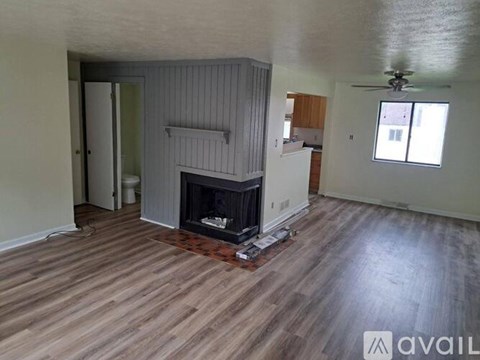 A living room with a fireplace and a ceiling fan.
