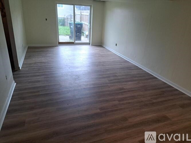 A room with wooden flooring and a sliding glass door leading outside.