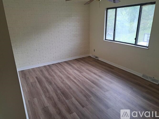 A room with wooden flooring and a window letting in natural light.