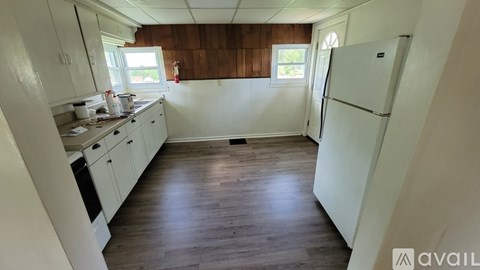 A kitchen with white cabinets and a white fridge.