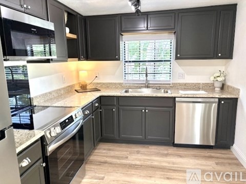 A kitchen with black cabinets and stainless steel appliances.