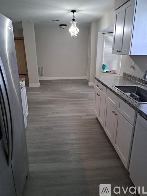 A kitchen with a refrigerator on the left and cabinets on the right.