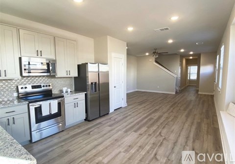 A kitchen with white cabinets and a wooden floor.