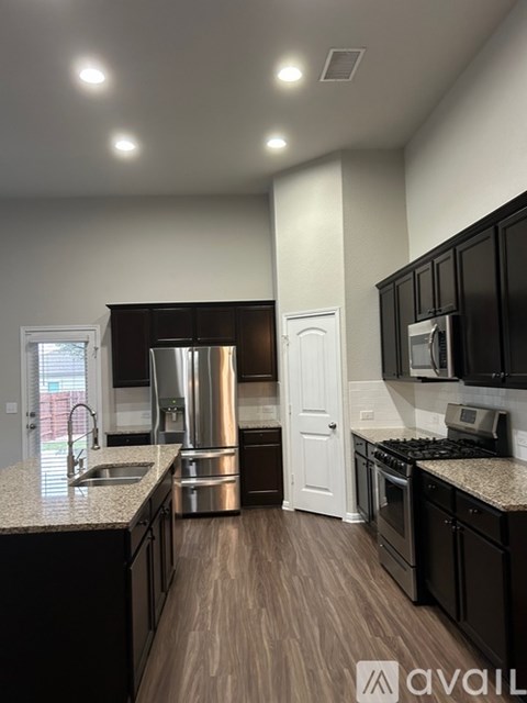 A modern kitchen with black cabinets and stainless steel appliances.