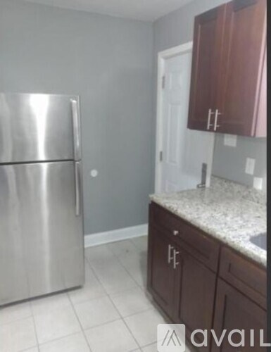 A kitchen with a stainless steel refrigerator and brown cabinets.