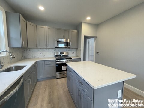 A kitchen with a white counter top and grey cabinets.