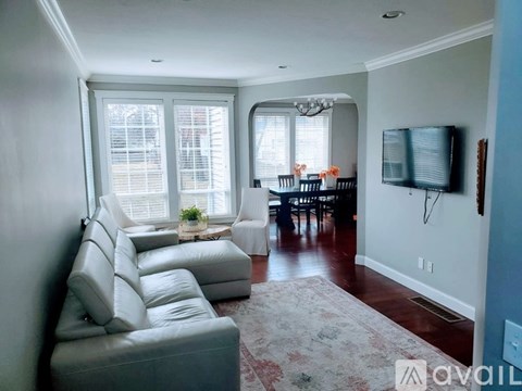 A living room with a grey couch and a television on the wall.