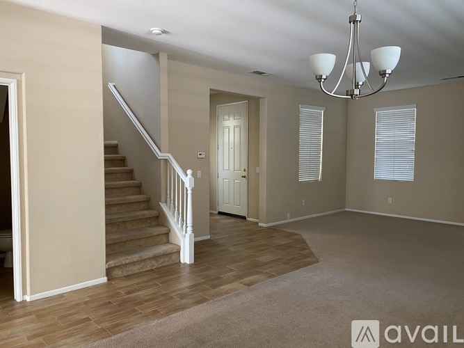 A spacious room with a staircase and a chandelier.