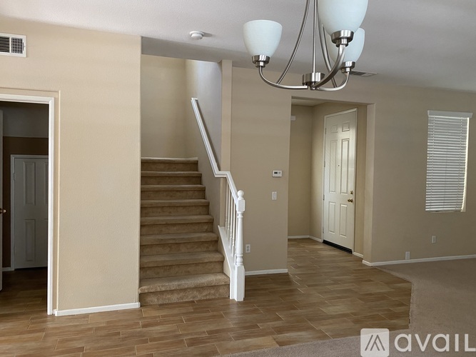 A living room with a staircase and a chandelier.