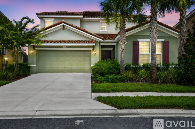 A house with a garage and palm trees in front.