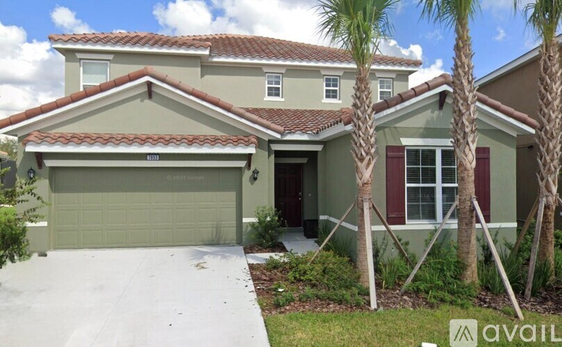 A house with a garage and palm trees in front.