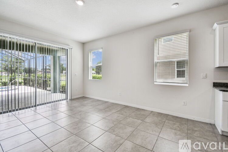 A spacious room with tiled flooring and a sliding glass door leading to a pool area.