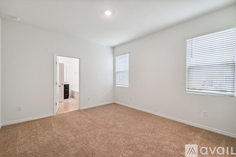 A room with a carpeted floor and a window with blinds.