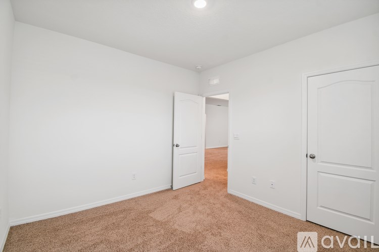 A room with white walls and carpeted floor with two doors.