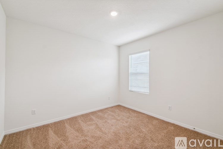 A room with a carpeted floor and a window with blinds.