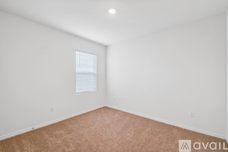A room with a carpeted floor and a window with blinds.