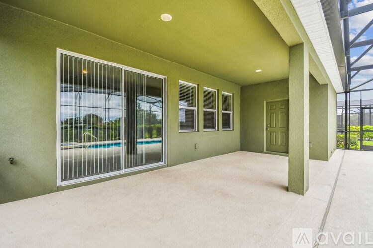 A large, empty room with a pool table and a glass wall overlooking a pool.