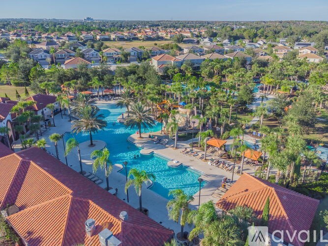 A bird's eye view of a resort with a swimming pool surrounded by palm trees.