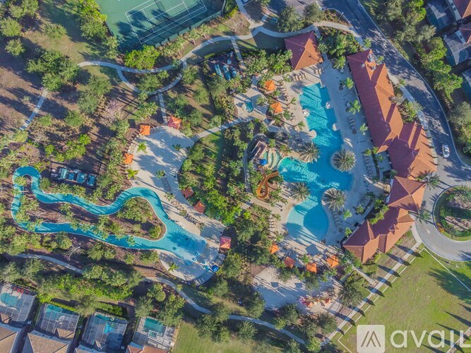 An aerial view of a resort with a large swimming pool and a winding blue water slide.