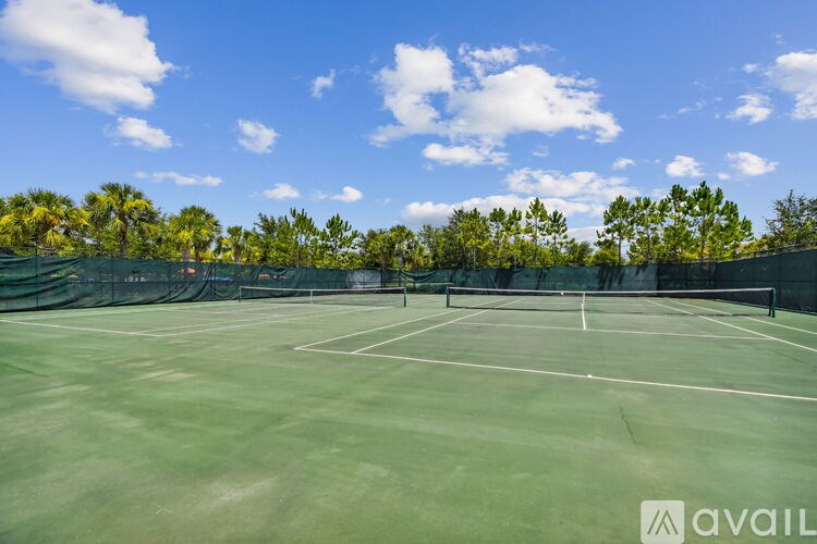 A tennis court surrounded by a fence and trees.