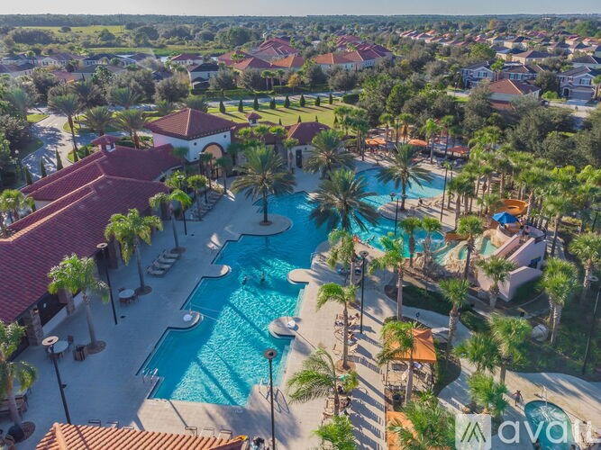 An aerial view of a resort with a swimming pool and palm trees.