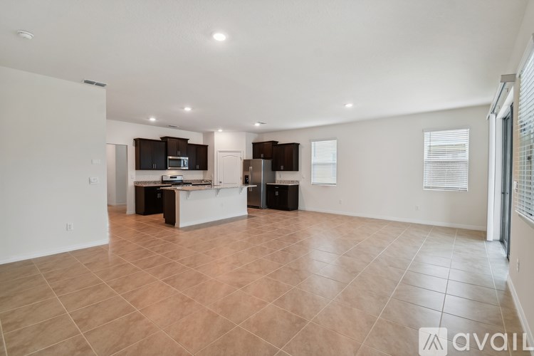 A spacious living room with a kitchen area in the background.