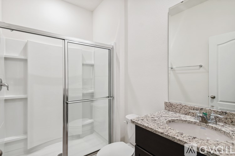 A bathroom with a glass shower door and a marble countertop.