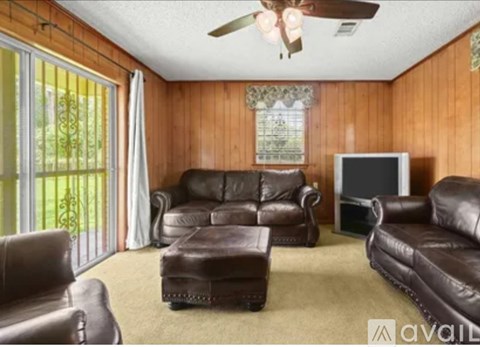 A living room with brown leather furniture and a ceiling fan.