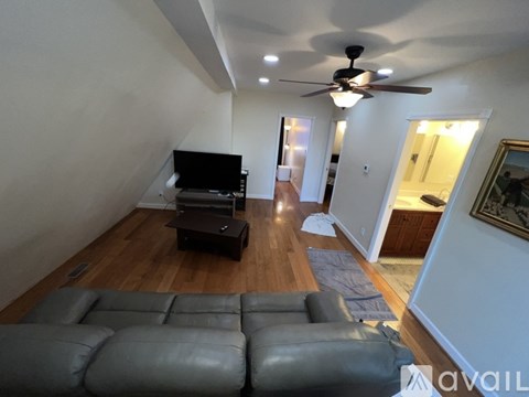 A living room with a grey leather sofa and a ceiling fan.