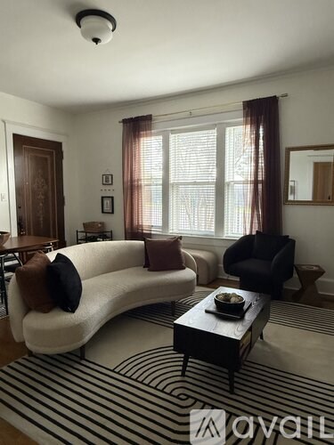 A living room with a white couch and a black and white striped rug.