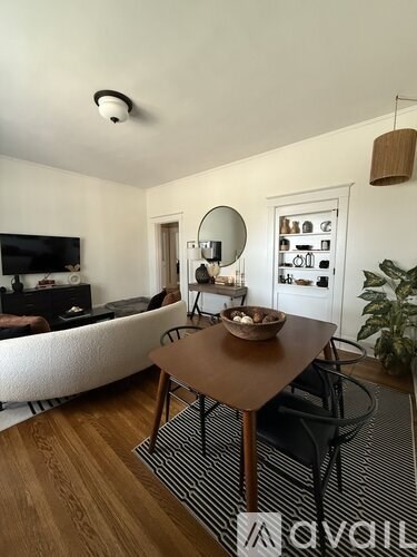 A living room with a white couch, a wooden table, and a black and white striped rug.