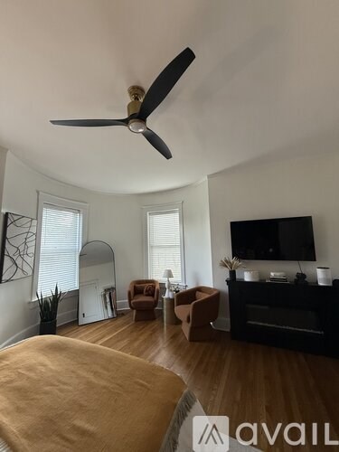 A living room with a fan, a television, and a brown sofa.