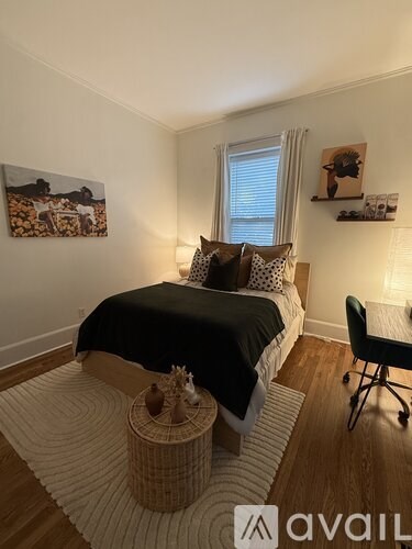 A bedroom with a bed, chair, and pictures on the wall.