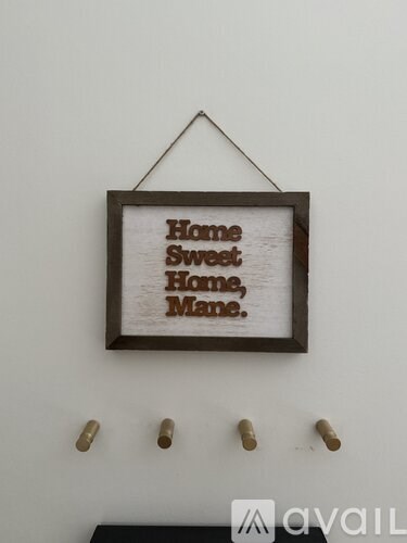 A picture frame with the text "Home Sweet Home, Home, Mane." hanging on a wall.