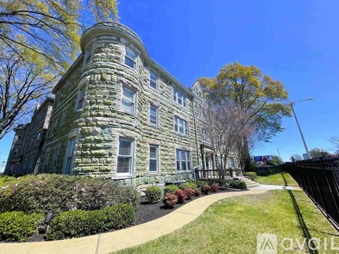 A large, old building with a stone facade and a green lawn in front.
