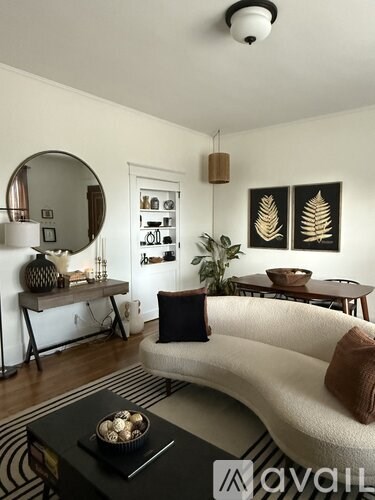 A living room with a white couch, a black coffee table, and a mirror on the wall.