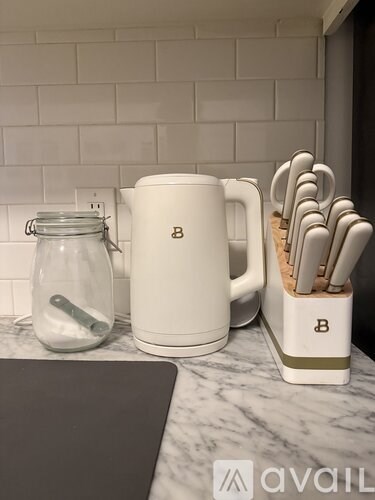 A kitchen counter with a white mug, a jar, and a set of knives.