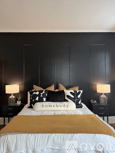 A bed with a white comforter and a pillow that says "homebody" is in the foreground.