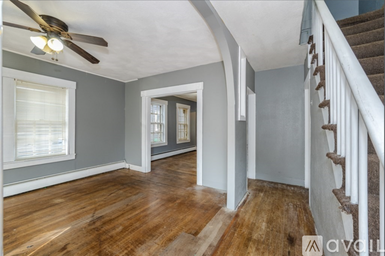 A room with a wooden floor and a staircase on the right side.