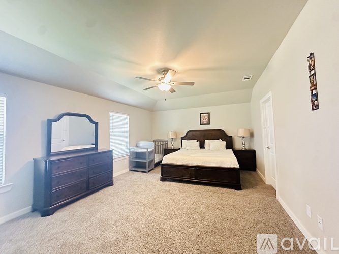 A bedroom with a large bed, a dresser, and a ceiling fan.