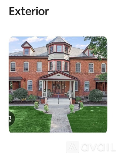 A large red brick house with a white trim and a large front porch.
