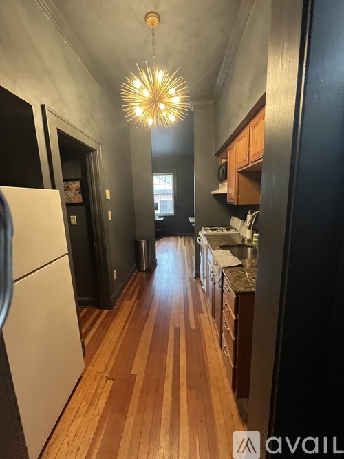 A kitchen with wooden floors and a white refrigerator.