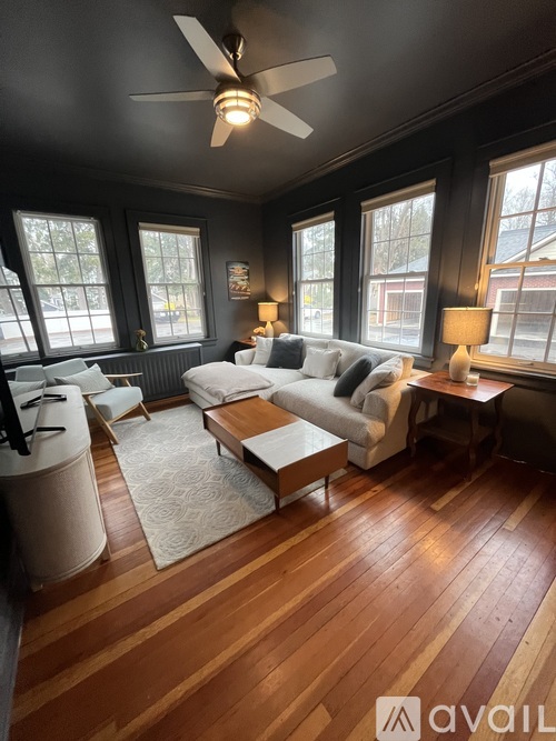 A living room with a white couch and a wooden floor.